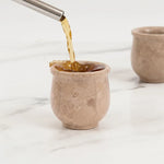 Drink being poured into a verona marble shot glass on a marble surface
