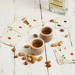 Pair of verona marble shot glasses filled for a poker night with cards and peanuts
