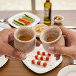 Two hands toasting with verona marble shot glasses over a table of appetizers
