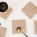 Verona square marble coasters styled with gold cutlery on an off white surface