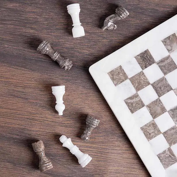 White and grey oceanic marble chess set 12 inch — pieces scattered on dark wood surface showing white marble and oceanic grey stone detail by RADICALn