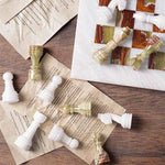 White marble and green onyx chess pieces scattered on book pages — board corner detail by RADICALn