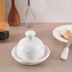 White marble butter dish with domed lid and matching marble spreader knife on a kitchen table