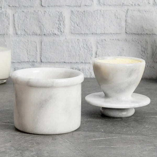 White marble butter keeper with butter packed in the lid next to its open crock base