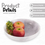 White marble fruit bowl holding an apple and an orange, showing the polished natural stone finish