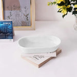 White marble oval tray on a desk with books, a calendar and flowers