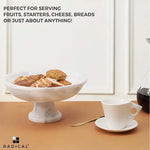 White marble pedestal bowl raised on a stem holding sliced bread and rolls beside a coffee cup