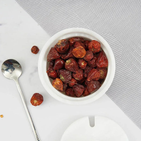 Overhead view of a white marble salt cellar holding dried red chillies with spoon and lid alongside, 4 inches in diameter and 3.5 inches tall