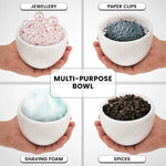 White marble bowl held in hand holding shaving foam, jewellery, paper clips and spices