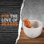 White marble shaving bowl holding a wooden shaving brush on a wood counter