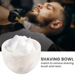 White marble shaving bowl full of lather with a barbershop shave in the background