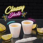 Two white marble shot glasses filled with liquor beside lemon wedges and salt