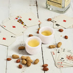 Pair of white marble shot glasses filled for a poker night with cards and peanuts