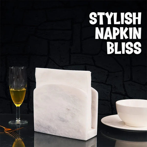 White marble table napkin holder with folded napkins beside a wine glass and gold fork