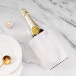 White marble hexagon wine chiller lying beside a champagne bottle on marble