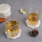 White onyx octagon marble coasters under two whiskey glasses on a white table