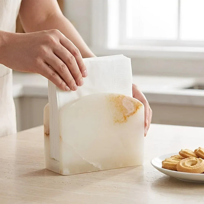 Hand pulling a white napkin from a white onyx marble napkin holder in a kitchen