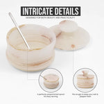 White onyx marble salt cellar with lid off and spoon inside, showing the snug-fitting notched lid and proportioned serving spoon