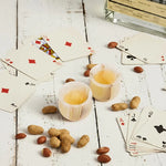 Pair of white onyx marble shot glasses filled for a poker night with cards and peanuts