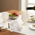 Red wine poured into a white onyx marble wine glass at a set dinner table